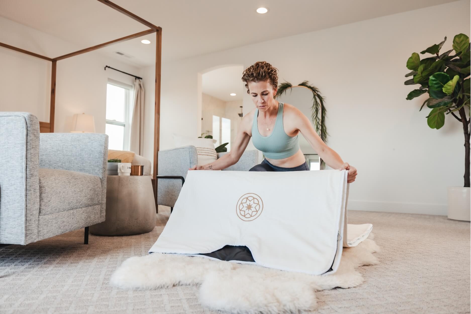 Woman preparing infrared sauna blanket at home, representing modern wellness routines and therapeutic heat rituals.