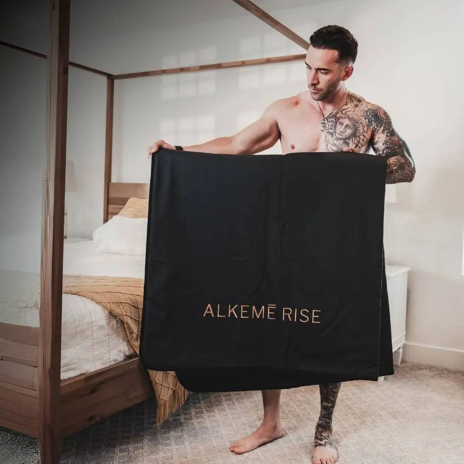 Man holding up the Alkemē Rise Infrared Sauna Blanket.
