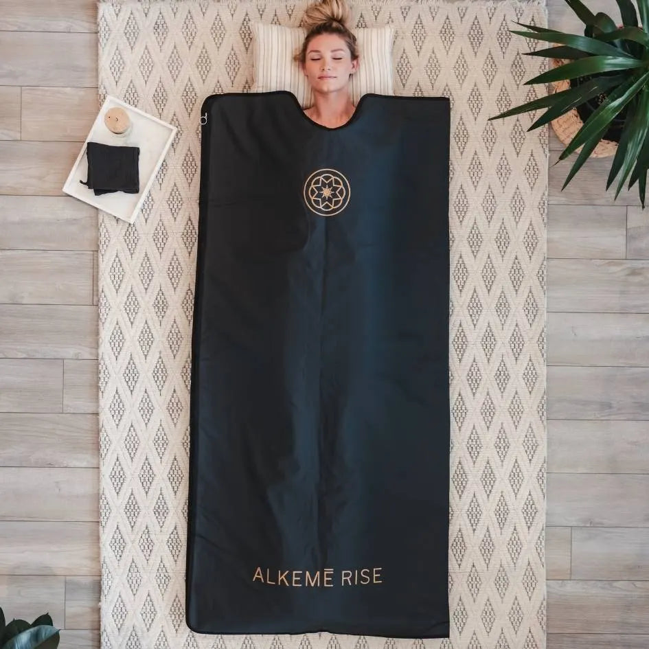 Blonde women laying peacefully in the black infrared sauna blanket.