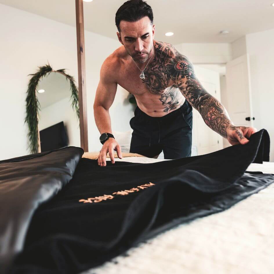man laying the towel insert inside his black infrared sauna blanket