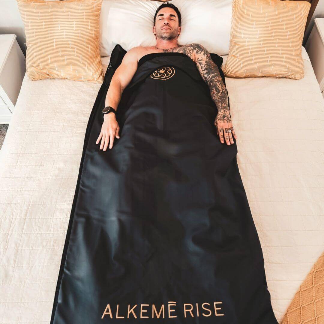 laying relaxing on his bed inside the infrared sauna blanket