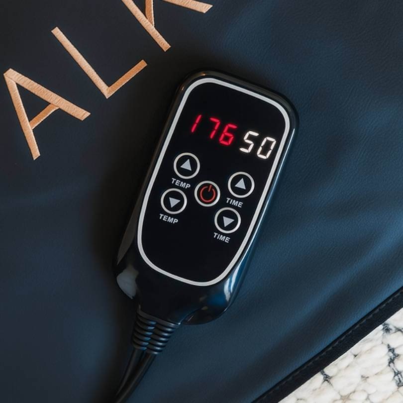 Close-up of Alkeme Rise infrared sauna blanket control panel showing adjustable time and heat settings.