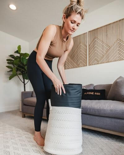 Woman storing an infrared sauna blanket in a cozy, modern home setting, showing how wellness rituals blend seamlessly into everyday routines and spaces.