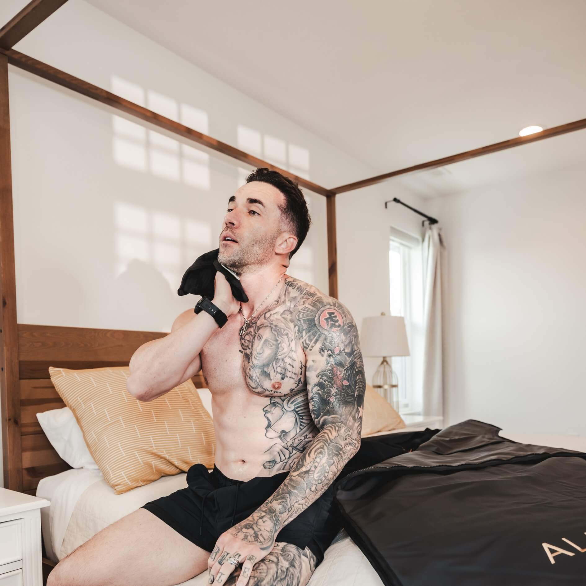 Man relaxing after a session with the Alkēme Rise black infrared sauna blanket, promoting effortless wellness and recovery at home.